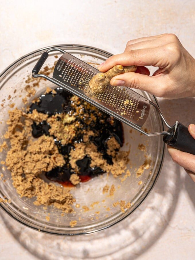 hand grating ginger over a bowl