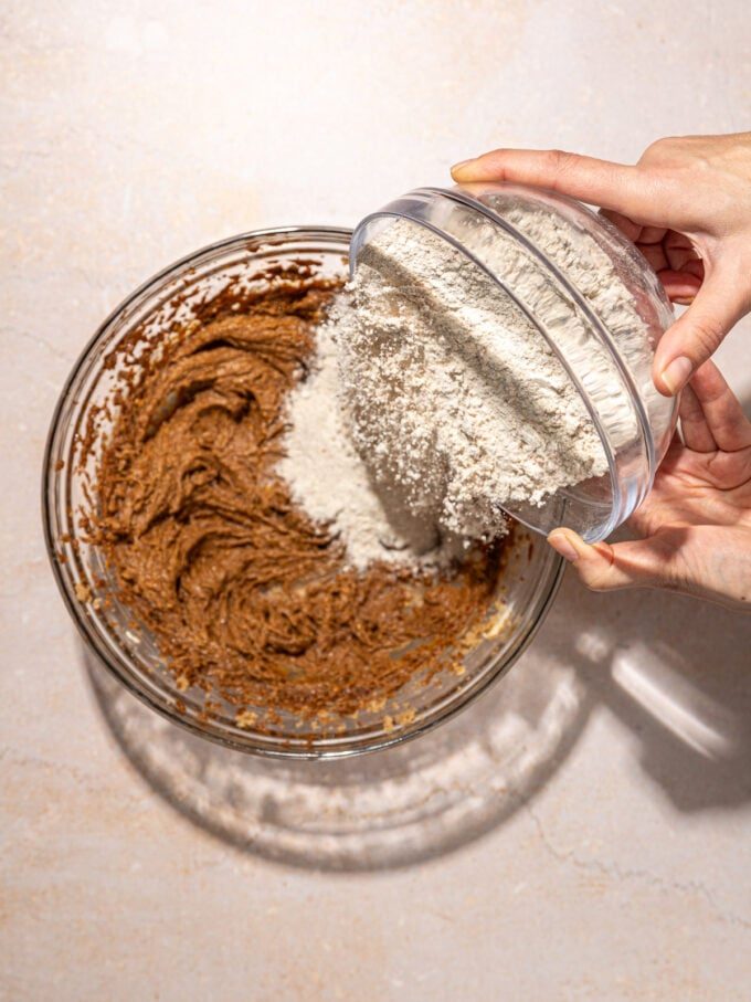 hand pouring flour into batter