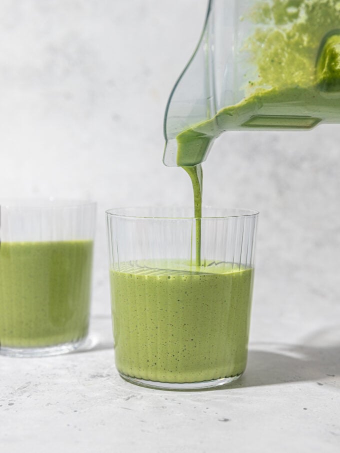 pouring kale smoothie into a glass