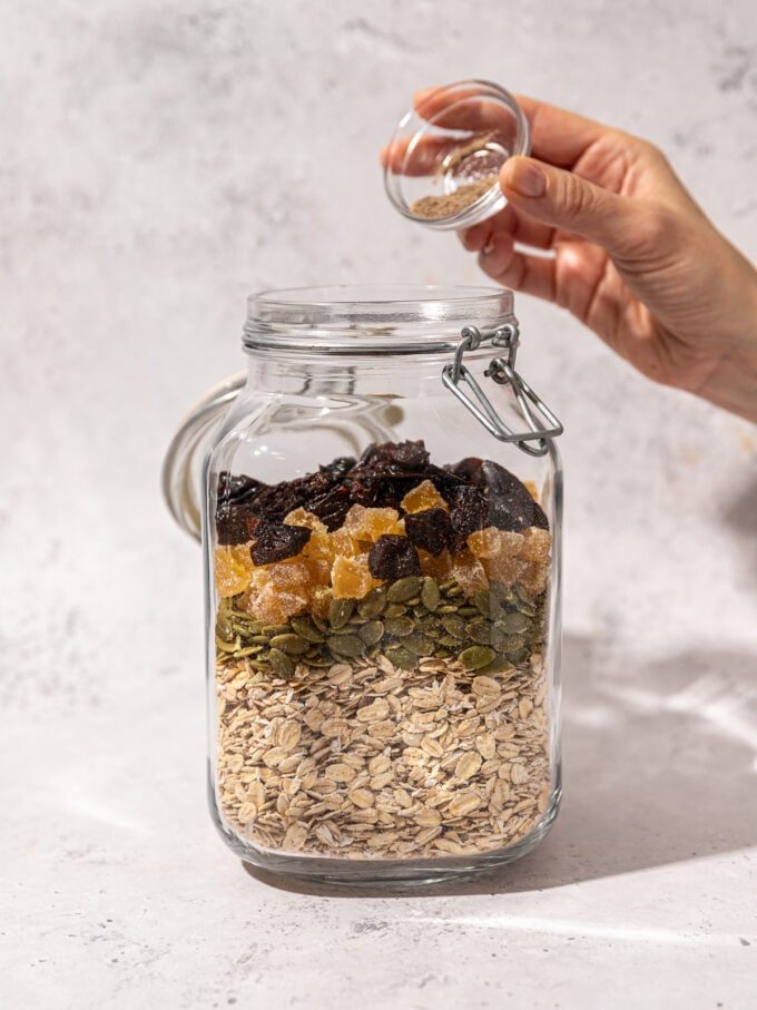 hand adding spice to muesli