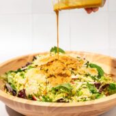 hand pouring dressing on crispy rice and brussels sprouts salad