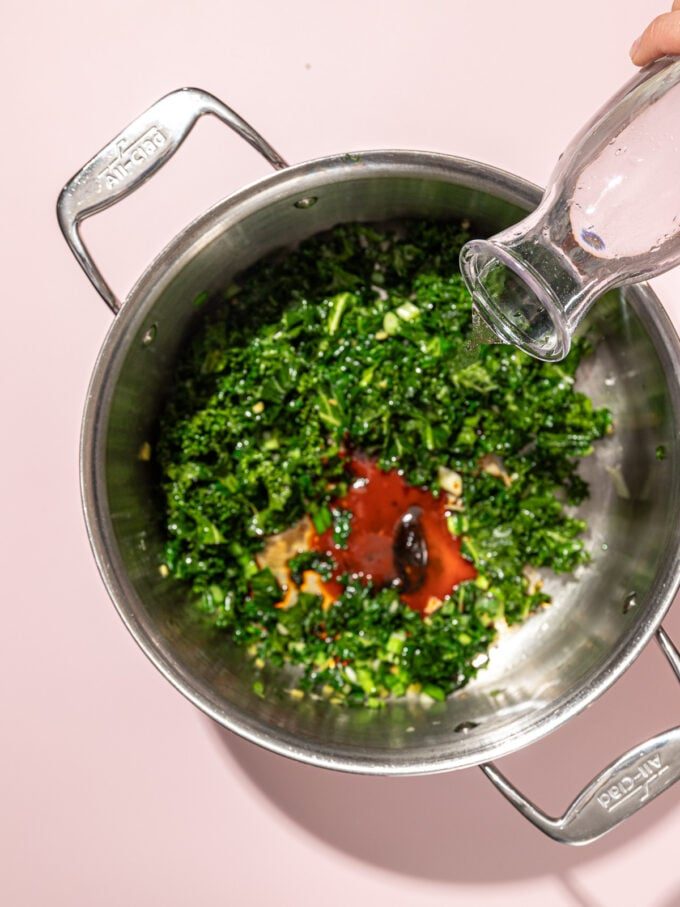 hand pouring water into pot of kale