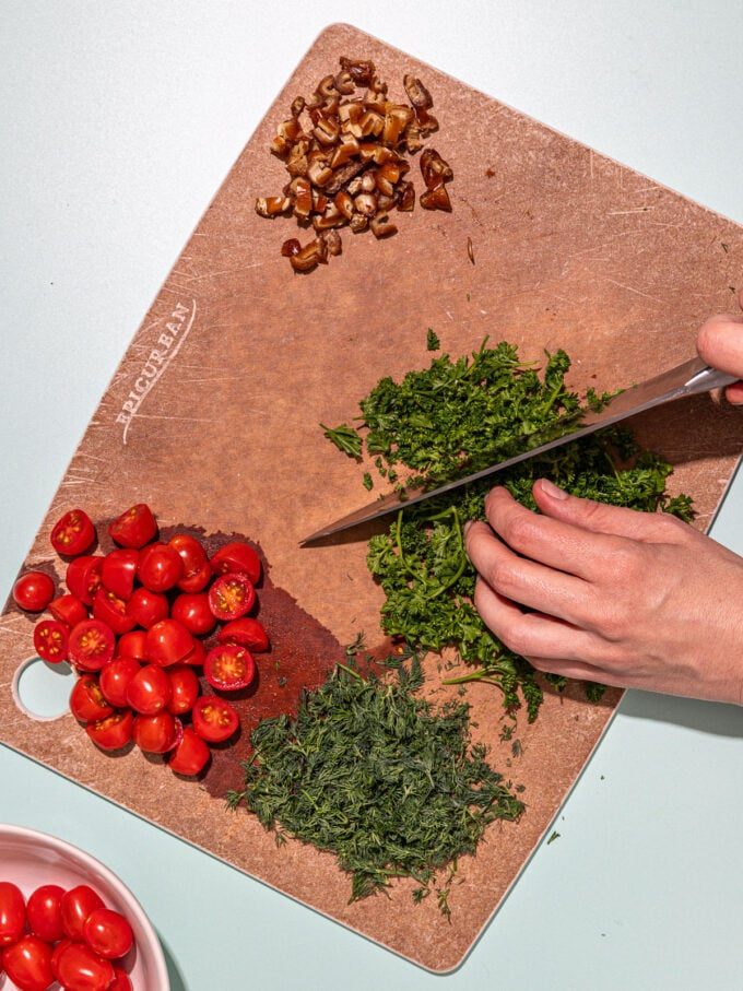 hand chopping parsley on wooden board