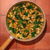 tofu, spinach and potatoes in a skillet on red brick