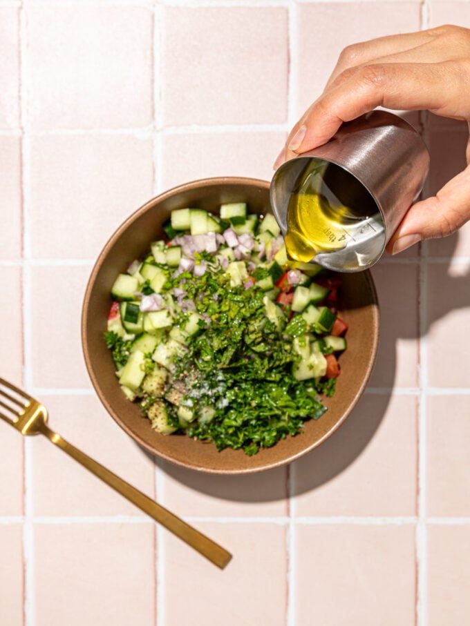 hand pouring oil into salad bowl