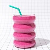 pink smoothie with green straw on black and white tiles
